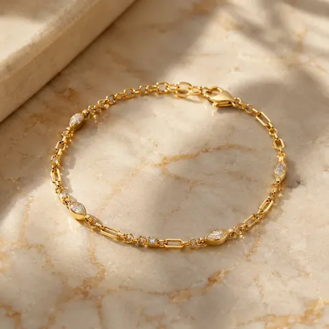 Gold bracelet with small gemstones on warm marble