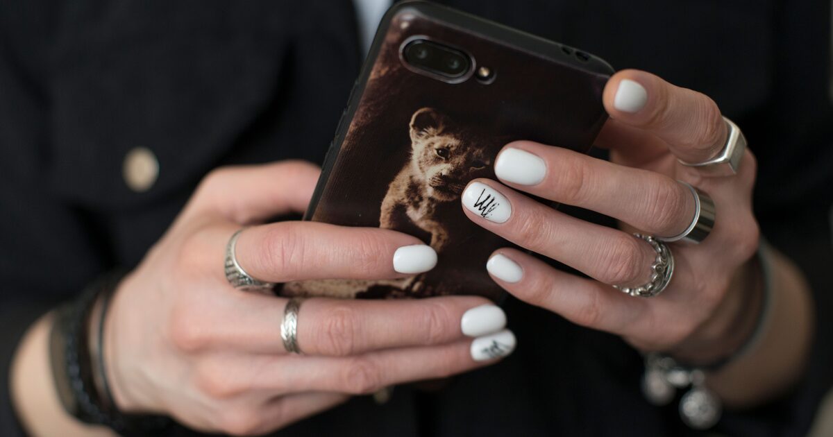 Ringed hands holding a smartphone