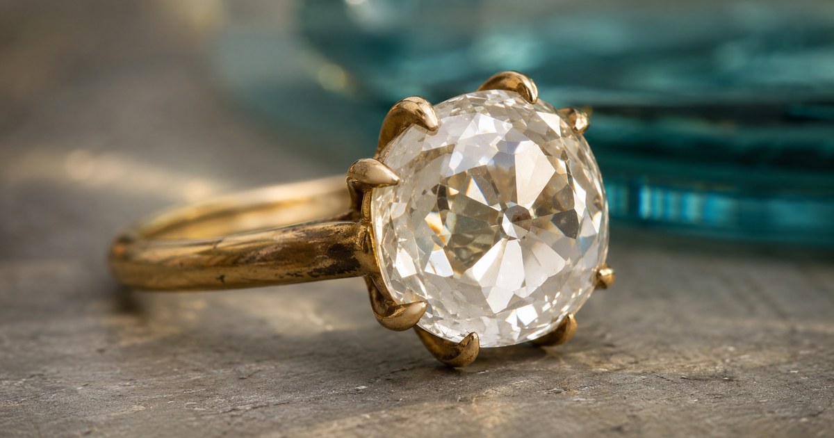 Antique diamond ring with a cushion-shaped old mine cut stone in a worn yellow-gold claw setting