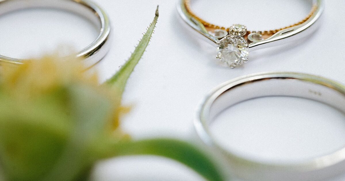 White-metal wedding bands and a solitaire ring arranged on a bright surface